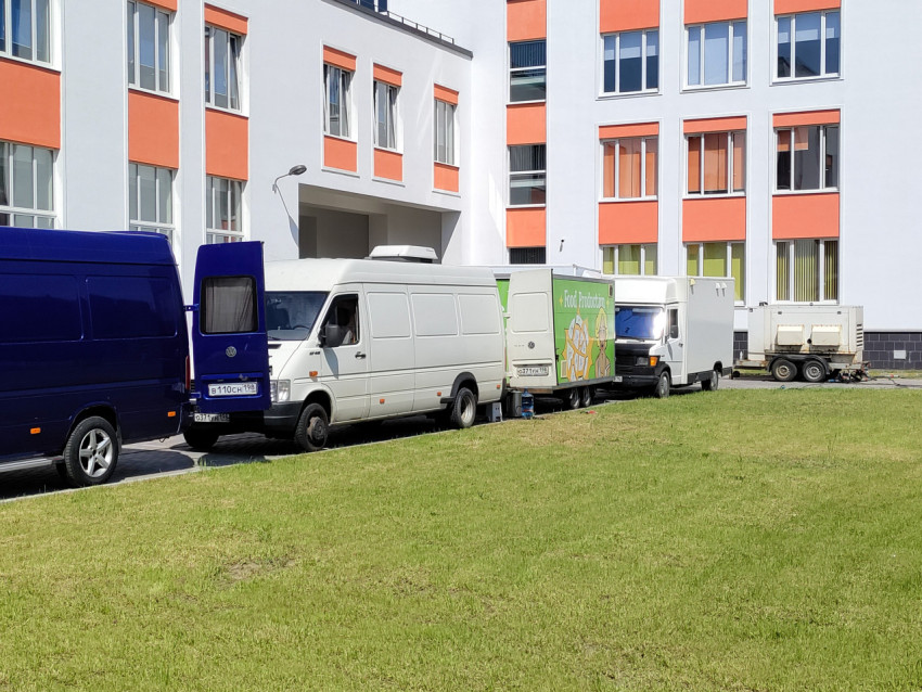 Ряд технических фургонов и трейлеров съемочной группы у здания школы