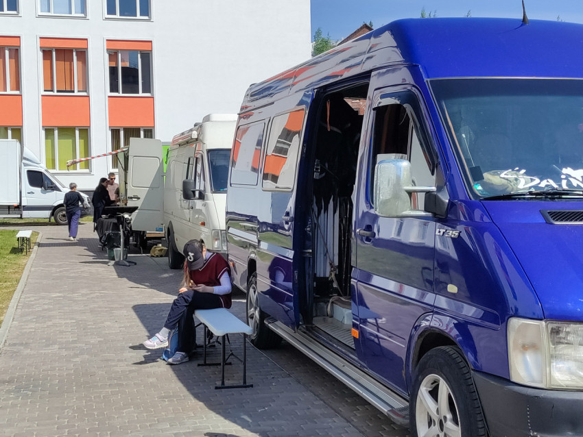 Зона работы съемочной группы с фургонами и персоналом у здания школы