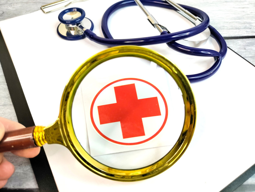 Лупа над медицинским символом и стетоскопом