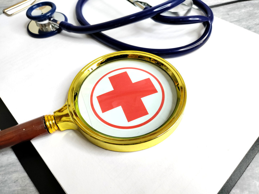 Лупа над символом медицины на планшете с документами