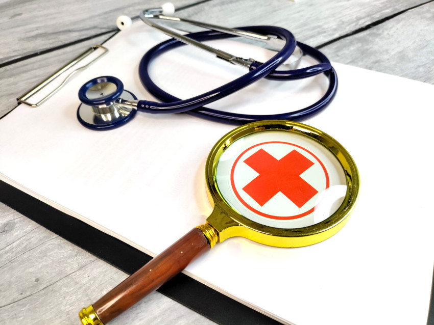 Лупа над символом здравоохранения и медицинскими инструментами