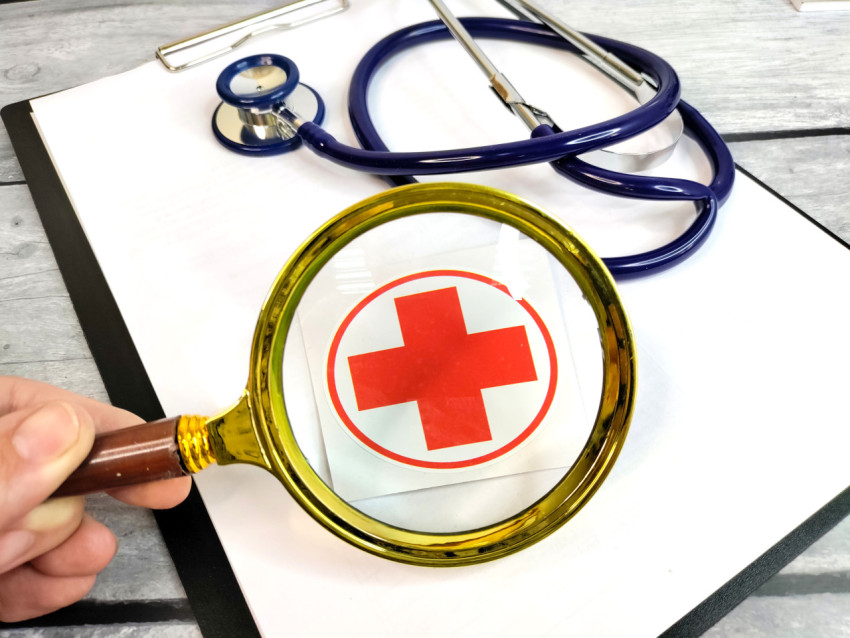 Увеличительное стекло над медицинским символом и стетоскопом