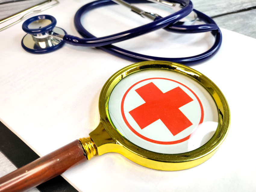 Увеличительное стекло с медицинским крестом на рабочем столе