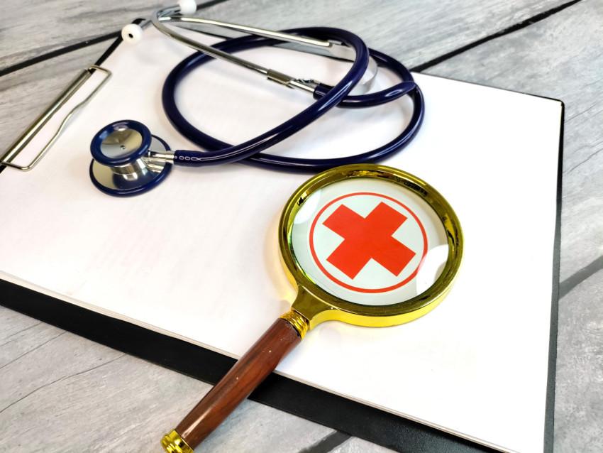 Увеличительное стекло над символом медицины и стетоскопом