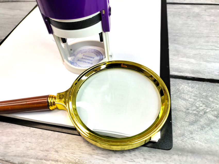 Увеличительное стекло рядом с автоматическим штампом на документе