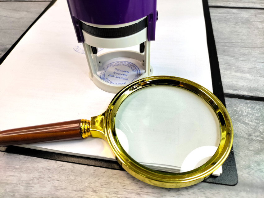 Увеличительное стекло и автоматический штамп на планшете с бумагой