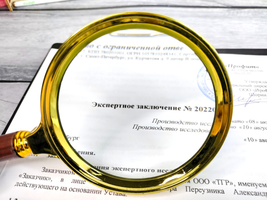 Увеличительное стекло на экспертном заключении при изучении документа