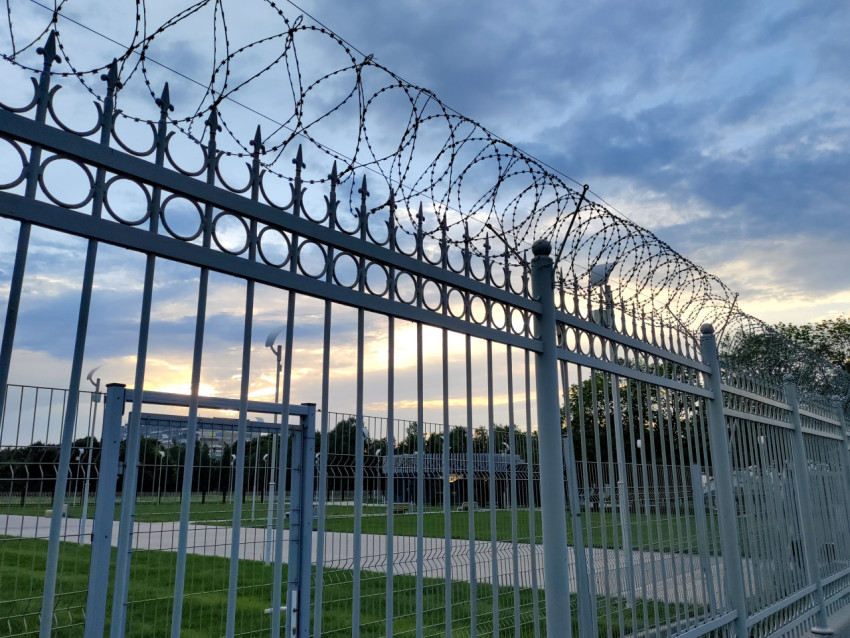 Металлическое ограждение с колючей проволокой на охраняемой территории