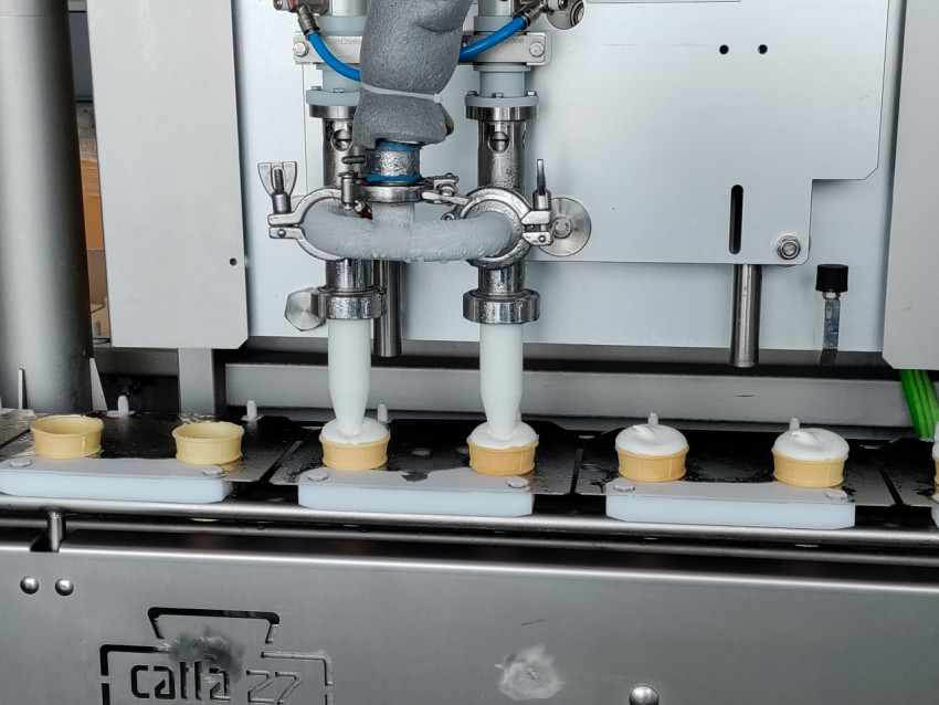 Процесс наполнения вафельных стаканчиков мороженым на конвейере