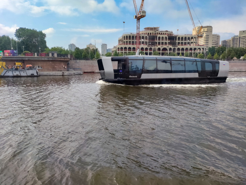 Электросудно на фоне набережной и строительных объектов
