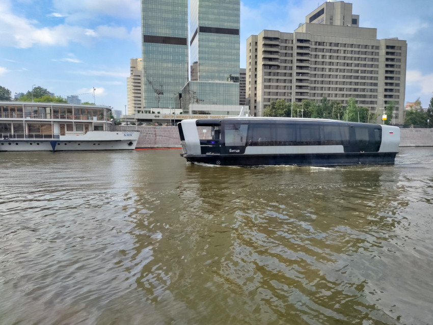 Речное электросудно на фоне многоэтажных зданий Москвы