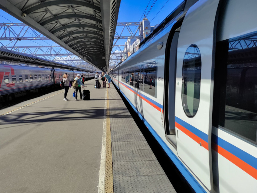 Пассажиры на платформе рядом с поездом «Сапсан» под навесом вокзала