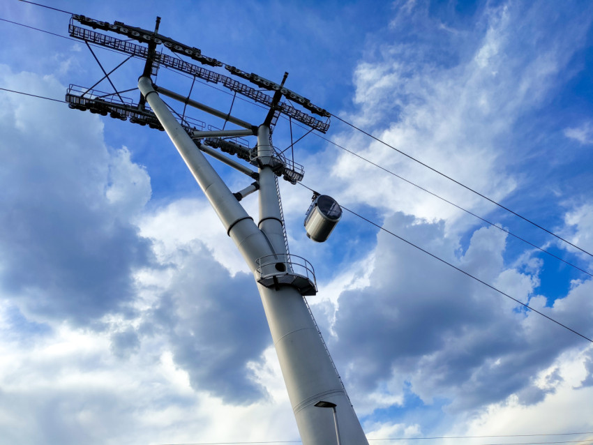 Опора канатной дороги и кабина на фоне облачного неба