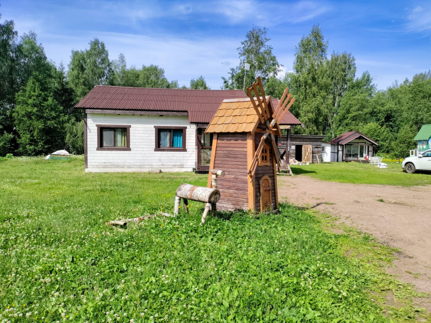 Декоративная мельница на участке рядом с гостевым домом и грунтовой дорожкой
