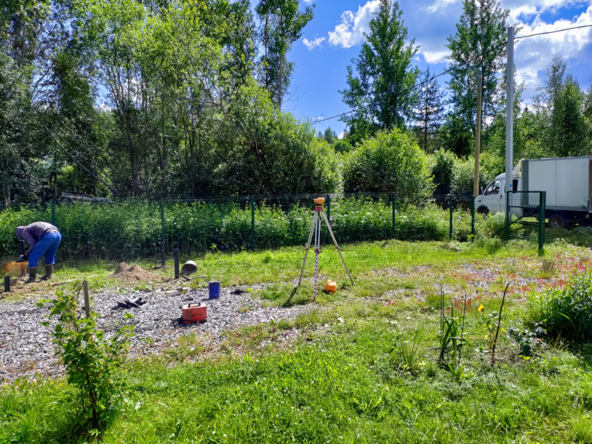 Геодезический штатив и монтаж свайного фундамента на участке со сваями и садовой зоной