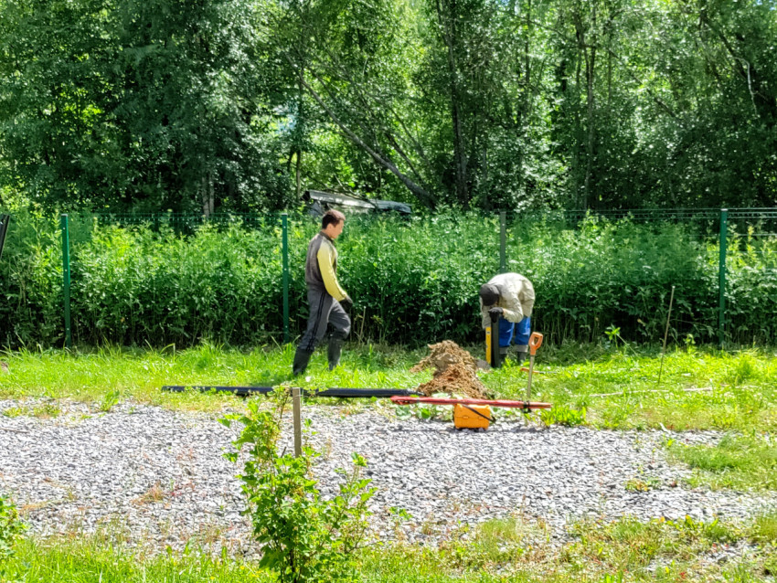 Рабочие подходят к точке установки сваи на площадке свайного фундамента у ограждения