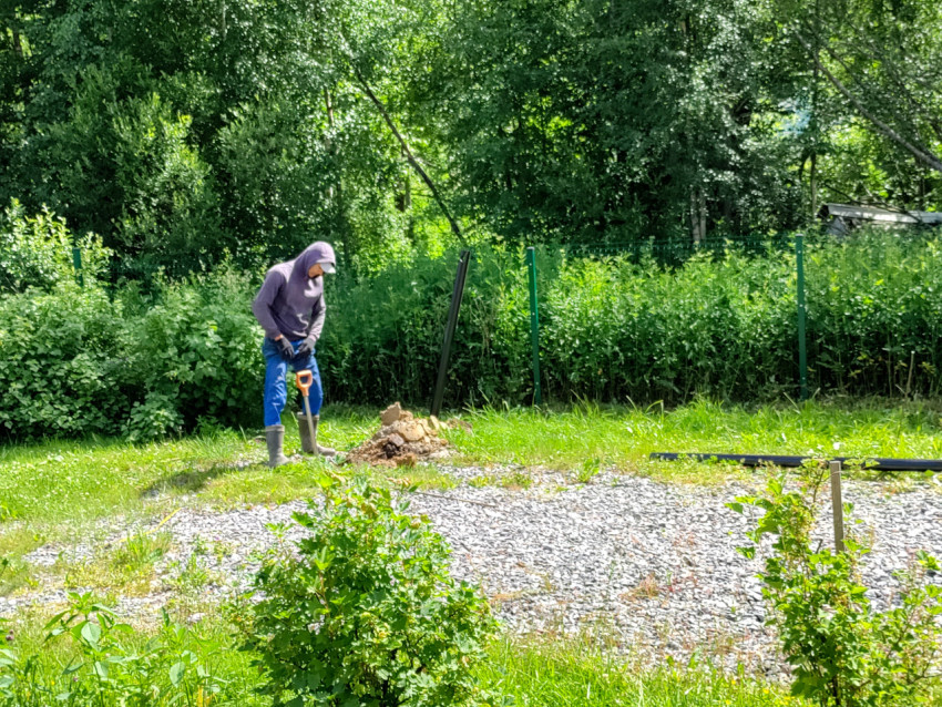 Подготовленная лунка и металлическая свая рядом с инструментом на участке