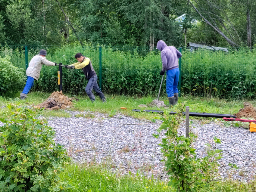Бригада устанавливает сваю свайного фундамента с ручным приспособлением на участке