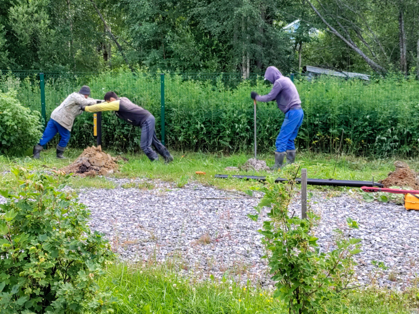 Рабочие фиксируют и уплотняют основание вокруг установленной сваи свайного фундамента