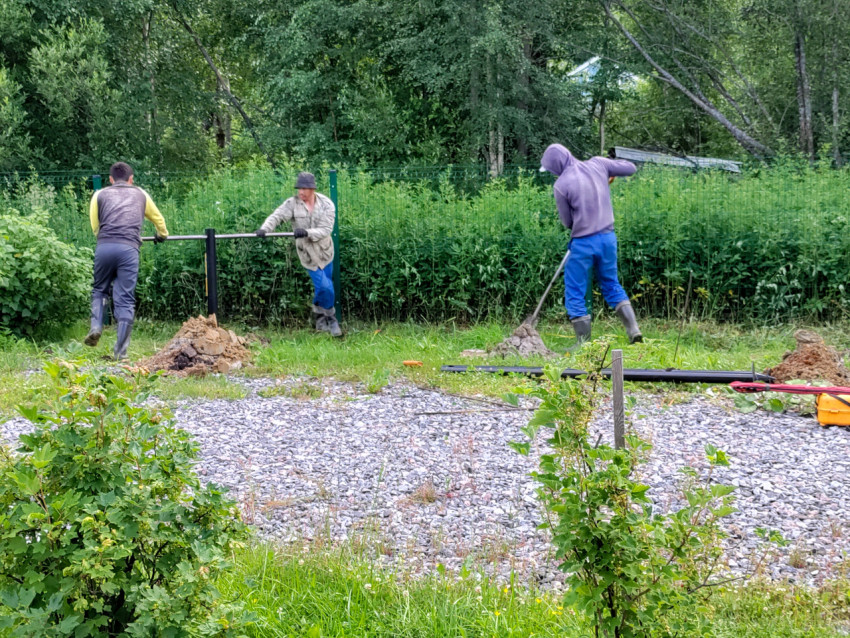 Рабочие выравнивают установленную сваю и подают грунт при монтаже свайного фундамента