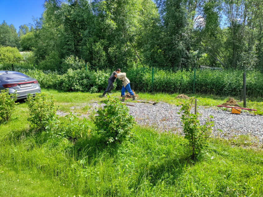 Двое рабочих завинчивают винтовую сваю ручным воротком при устройстве свайного фундамента