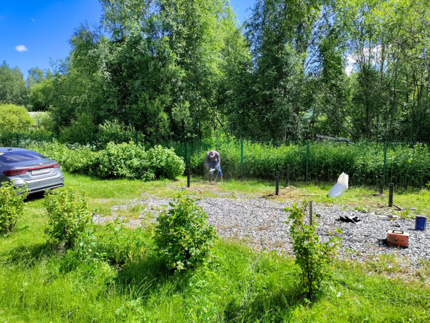 Рабочий фиксирует металлическую сваю механизированным инструментом при устройстве свайного фундамента