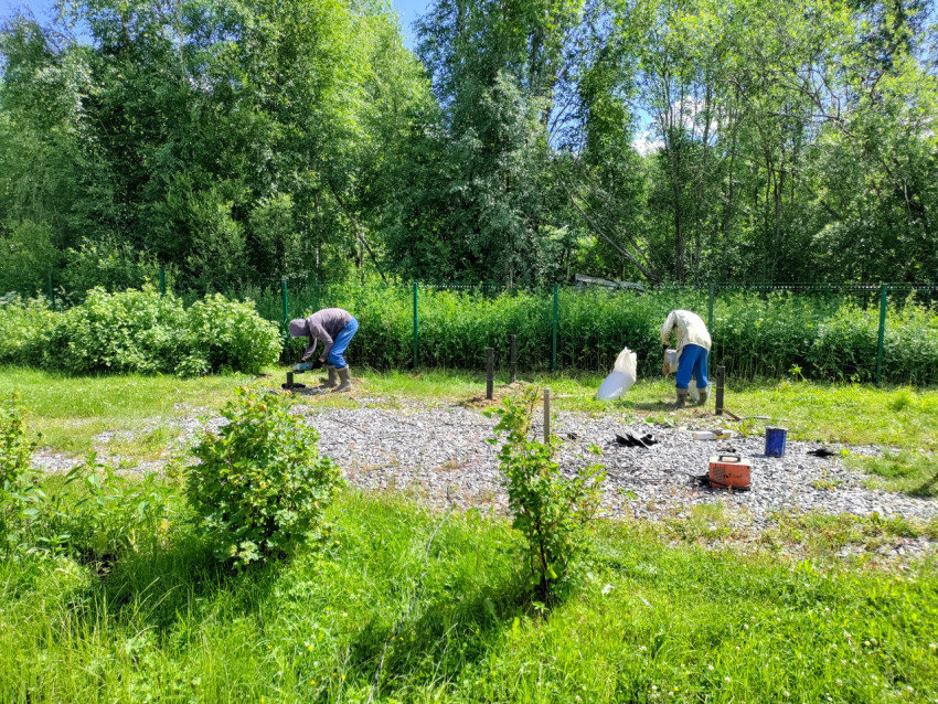 Два рабочих выполняют монтаж свайного фундамента на щебеночной площадке