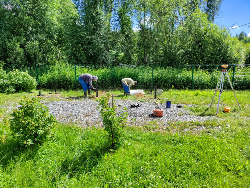 Рабочие выполняют подсыпку и выверку отметок при установке свайного фундамента