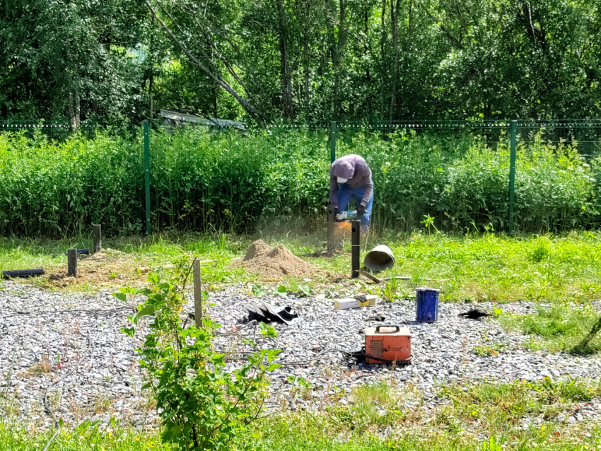 Резка металлической сваи болгаркой на участке устройства свайного фундамента у лесной кромки