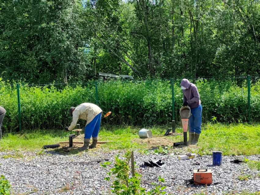 Рабочие выполняют ручные операции при установке винтовых свай свайного фундамента