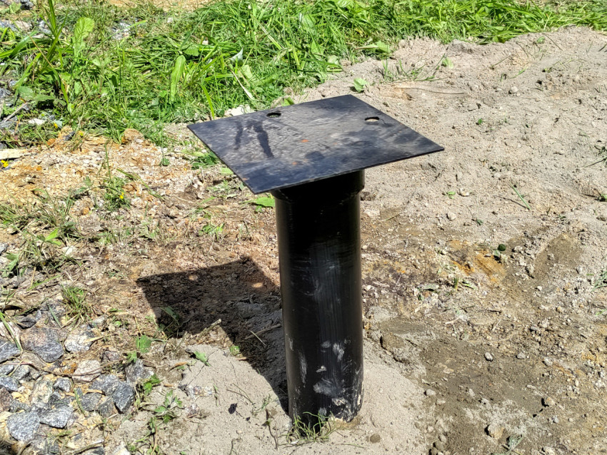 Металлическая свая фундамента под дом на границе щебёночной отсыпки и грунта