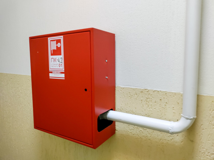 Пожарный шкаф с маркировкой ПК на стене в коридоре здания