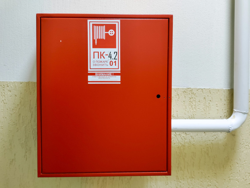Фронтальный вид пожарного шкафа с наклейкой ПК на светлой стене