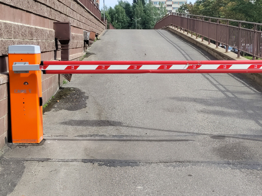 Шлагбаум CAME перекрывает подъём на пандус возле здания и металлического ограждения