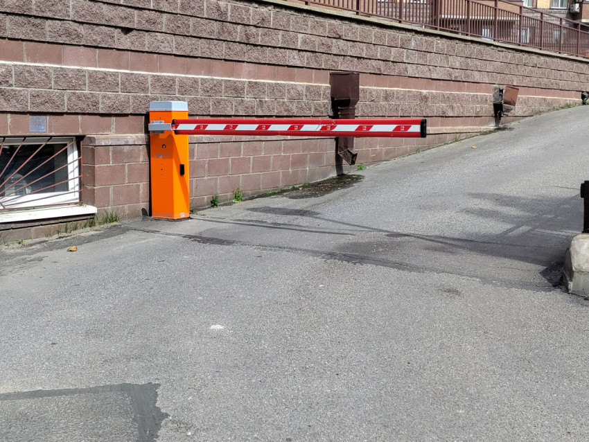 Автоматический шлагбаум на въезде к зданию у стены из облицовочного камня