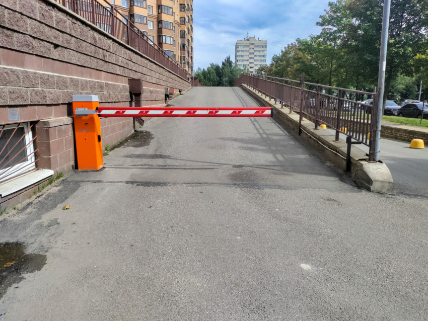 Шлагбаум на въезде к пандусу в жилом районе рядом с ограждением и парковочной площадкой