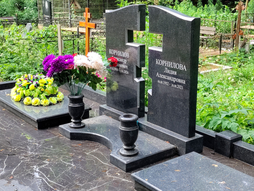 Двойной гранитный памятник с вазами и свежими букетами на могиле