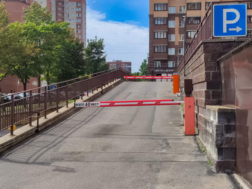 Въездной пандус на парковку со шлагбаумом и вывеской «Цветы и декор»