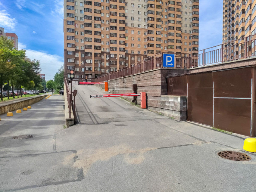 Въезд на парковку у жилого дома со шлагбаумом и знаком «P»