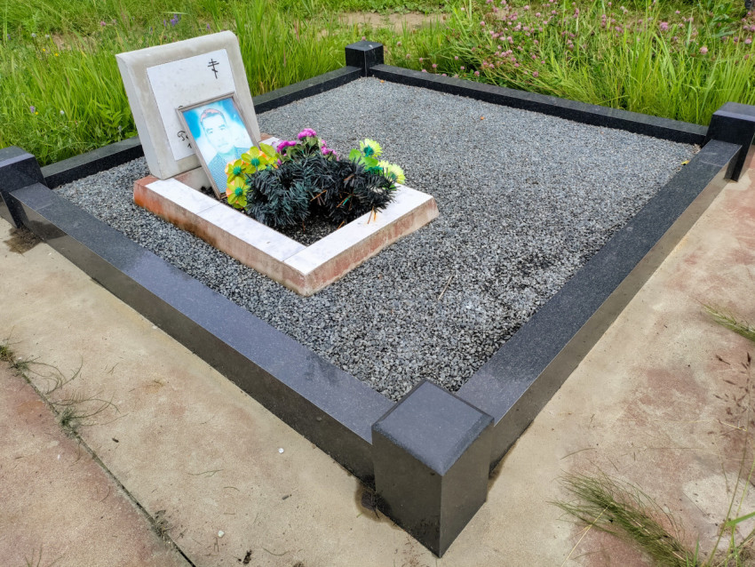 Могила с гранитным бордюром и памятником с православным крестом и фотографией