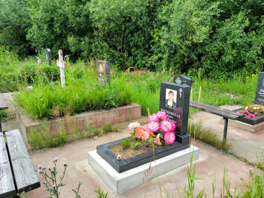 Могильный участок с гранитным памятником, цветами и лавочками на кладбище