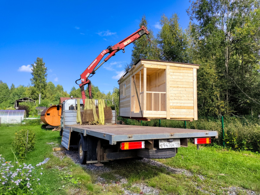 Разгрузка деревянной бытовки краном-манипулятором рядом с частным домом