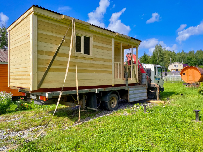 Грузовик-манипулятор с модульной деревянной бытовкой подготовлен к разгрузке на участке с винтовыми сваями