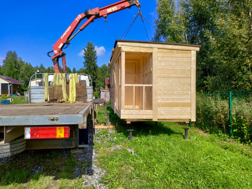 Подвешенный деревянный модуль на стропах у грузовика с манипулятором