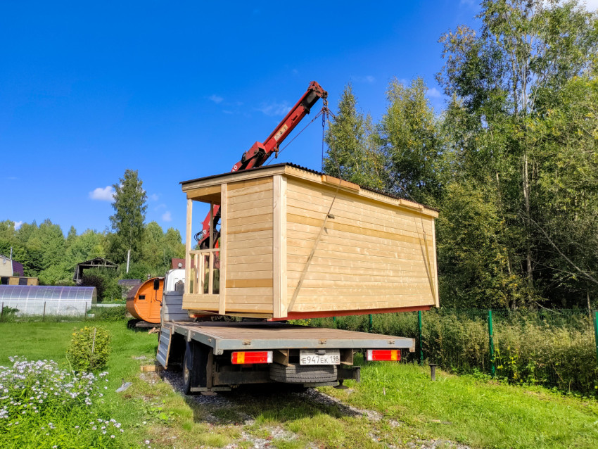 Кран-манипулятор поднимает деревянный модульный дом над участком для точной установки