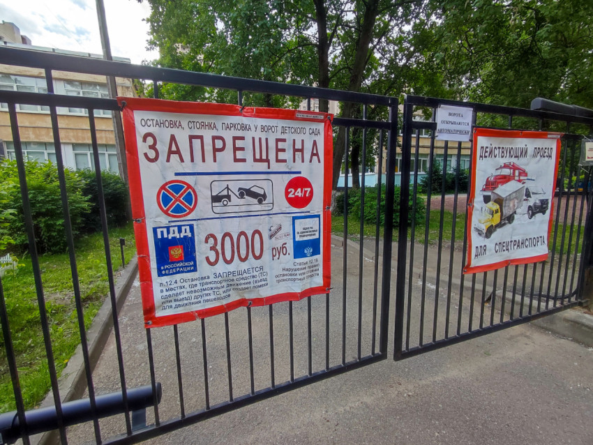 Предупреждающий плакат о запрете парковки у ворот детского сада на фоне дворового проезда