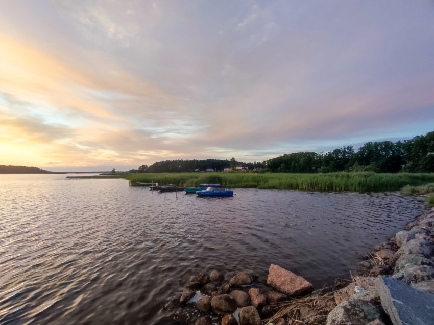 Причал с лодками на берегу водоема в вечернем свете заката