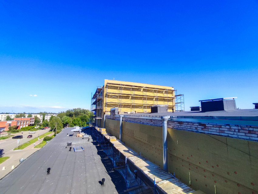 Панорама плоской крыши с фасадным утеплением и лесами над городской улицей