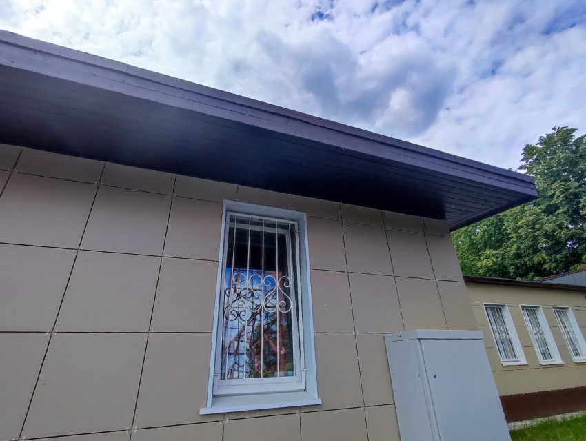 Фасад модульного здания с окном в решётке и металлической дверью