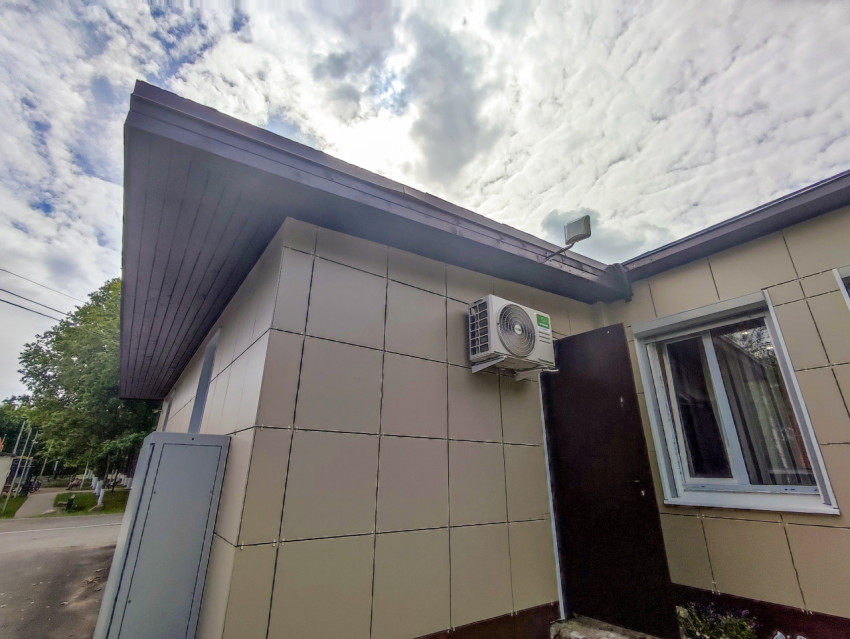 Угол служебного здания с внешним блоком кондиционера и открытой дверью